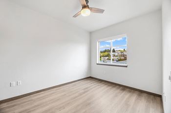 a living room with white walls and a window and a ceiling fan
